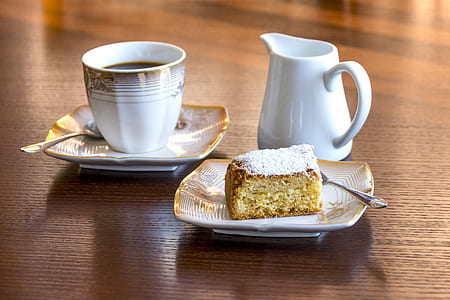 flatlay photography of teapot beside cup on saucer and slice of cake thumbnail