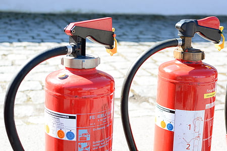 two red fire extinguishers on gray pavement thumbnail