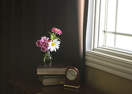 white and pink cluster flower in glass vase on brown books thumbnail