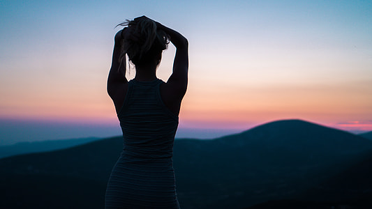 silhouette of woman facing mountain with hands on head thumbnail