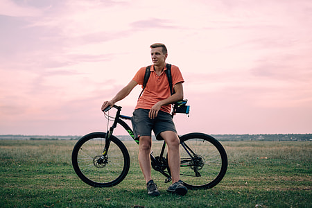 man leaning on black bicycle on open field thumbnail