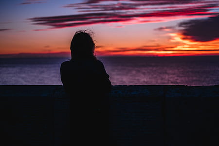 silhouette photography of person facing body of water thumbnail