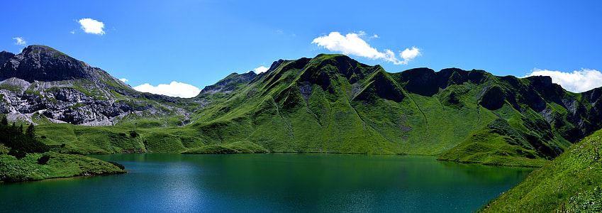 landscape photography of green mountain with lake at day time thumbnail