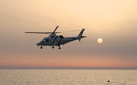 white helicopter hovering above body of water thumbnail