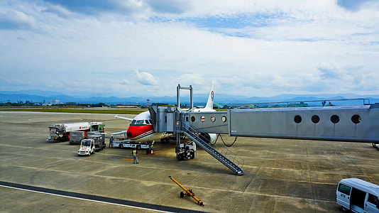 white and red plane in the airport loading passengers thumbnail
