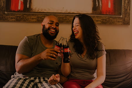 Two Laughing Man and Woman While Holding Coca-cola Glass Bottles thumbnail