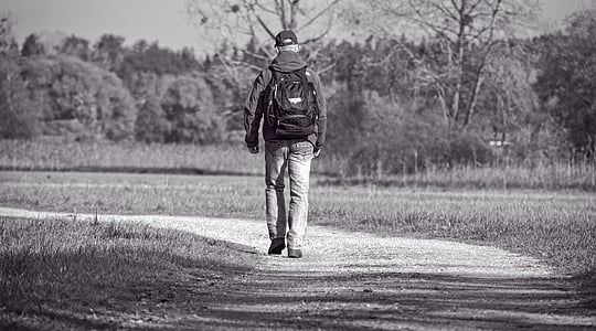 person in backpack walks on the road during daytime thumbnail