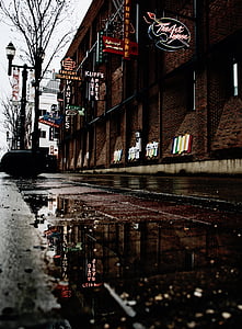 closeup photography of black concrete road near brown concrete building under white sky thumbnail