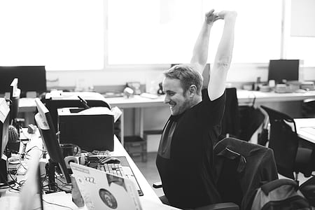 grayscale photo of man stretching arms in front of computer thumbnail