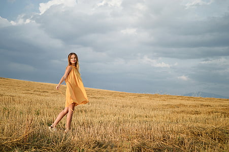 woman wearing yellow sleeveless mini dress walking on grass thumbnail