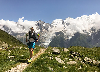 man running beside green grass during daytime thumbnail