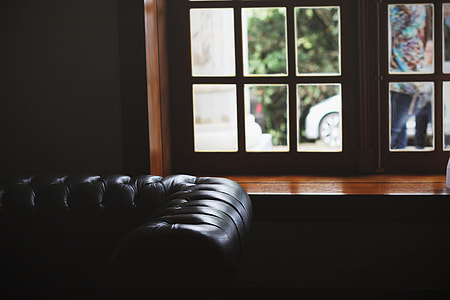 tufted black leather sofa near brown wooden framed window inside the room thumbnail