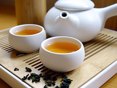 white ceramic teacup with tea near teapot on table thumbnail