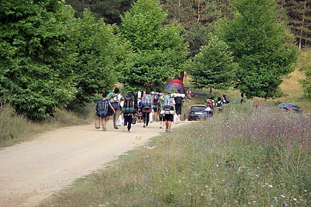 group of people carrying climbing backpack walking surrounded by trees and plants thumbnail