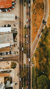 lot of cars on road surrounded by structures and trees thumbnail