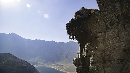 man wearing black long-sleeved shirt rock climbing during daytime landscape photography thumbnail