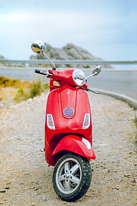 red motor scooter parking near body of water during daytime thumbnail