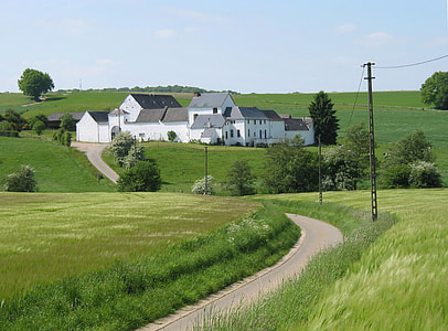 white concrete house between grass field at daytime thumbnail