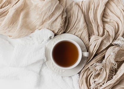 white ceramic teacup filled with brown liquid on white saucer thumbnail