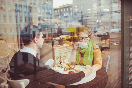 woman and man sitting on chair beside white wooden table thumbnail