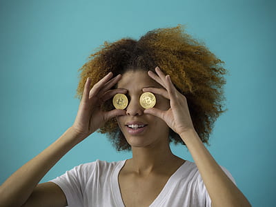woman holding two round gold-colored coins thumbnail