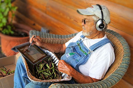 grandfather sitting on wicker brown armchair white using tablet computer thumbnail