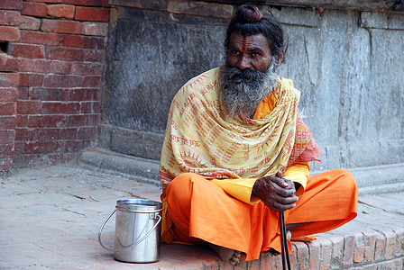 man in orange coat sitting near wall thumbnail