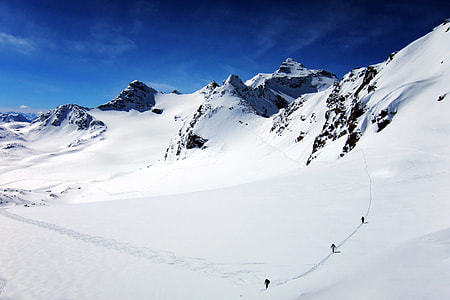 Three skiers traverse the snowy slopes at the Val Thorens in the French Alps on a sunny winter day thumbnail