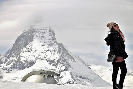 woman standing near snow-capped mountain during daytime thumbnail