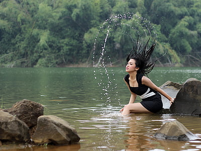 woman wearing black and white dress sitting near water thumbnail
