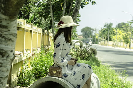 woman wearing white and blue floral dress sitting on bench outdoors thumbnail