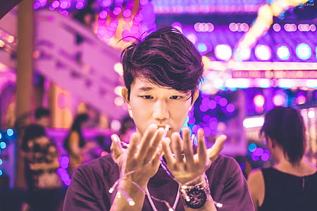 man looking at the string lights on his hands thumbnail