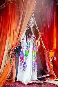 woman standing while holding orange and red curtain wearing multicolored angel sleeve long dress thumbnail