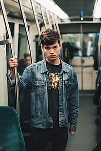 man standing inside train while holding bar thumbnail