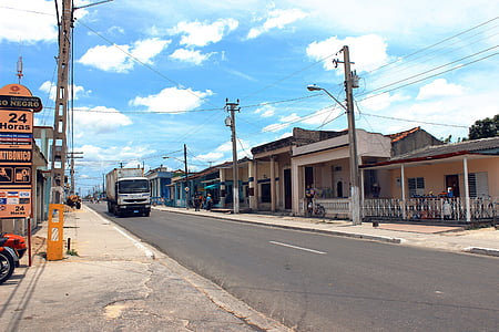 white box truck crossing road near houses at daytime thumbnail