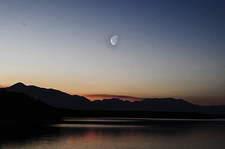 half moon over silhouette of mountains thumbnail