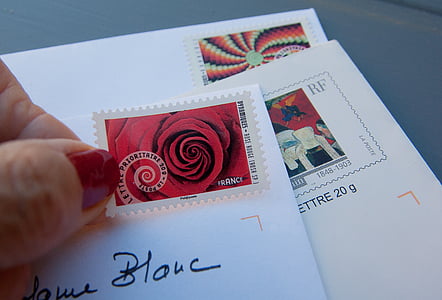 person holding red and white postage stamp thumbnail