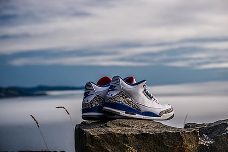 pair of white-black-and-blue Nike Air shoes on top of rock at daytime thumbnail