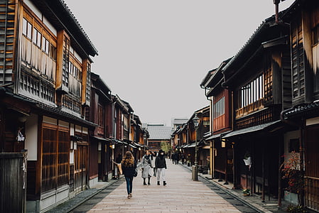 people walking on pathway between wooden houses during daytime thumbnail