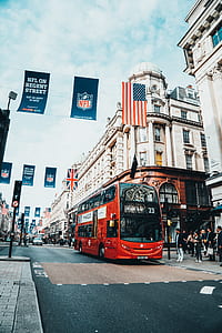 red double-decker bus on roadway beside white concrete building thumbnail