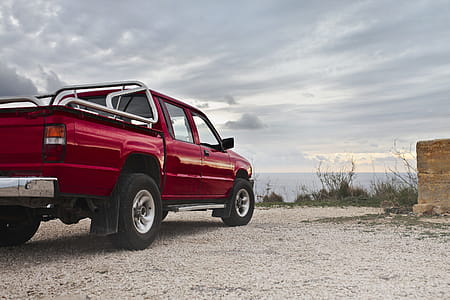 A red pick-up truck parked by the sea in an overcast weather thumbnail