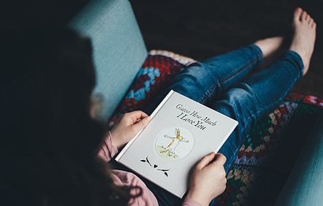 woman sitting of a couch reading book thumbnail