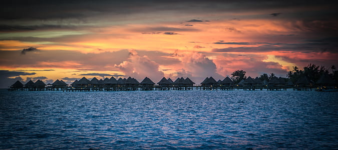 brown wooden cabana on body of water thumbnail