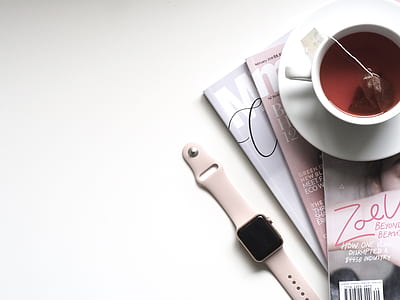 rose gold aluminum case Apple Watch with pink Sport Band beside white ceramic teacup filled with red liquid placed on white wooden board thumbnail