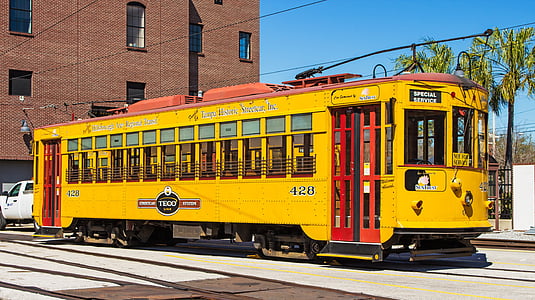 yellow and red train bus near building during daytime thumbnail