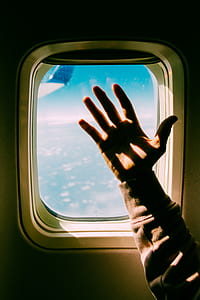 person's hand near airplane window thumbnail
