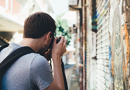 shallow focus photography of man holding camera during daytime thumbnail