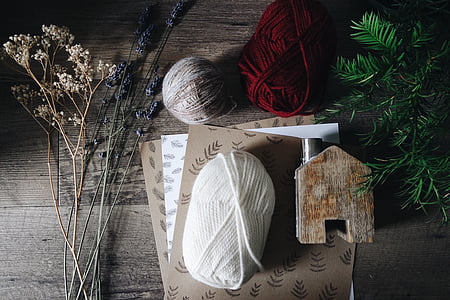 yarns on brown papers beside flowers on table thumbnail