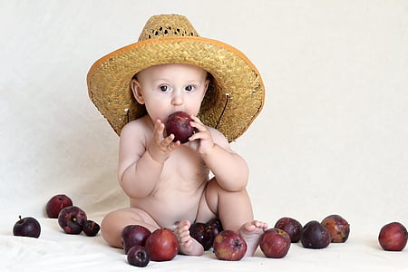 nude baby wearing brown straw hat eating red apple fruit thumbnail