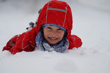 girl in red snowsuit lying on snow thumbnail